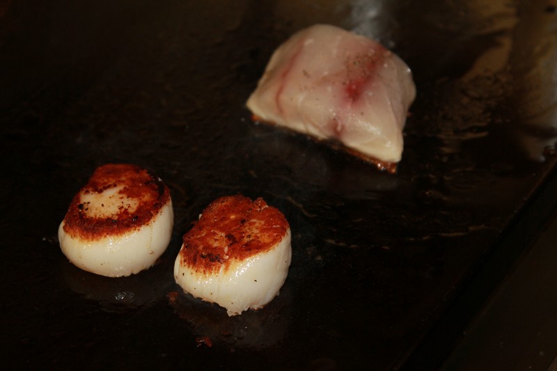Plancha cooking scallops and fish